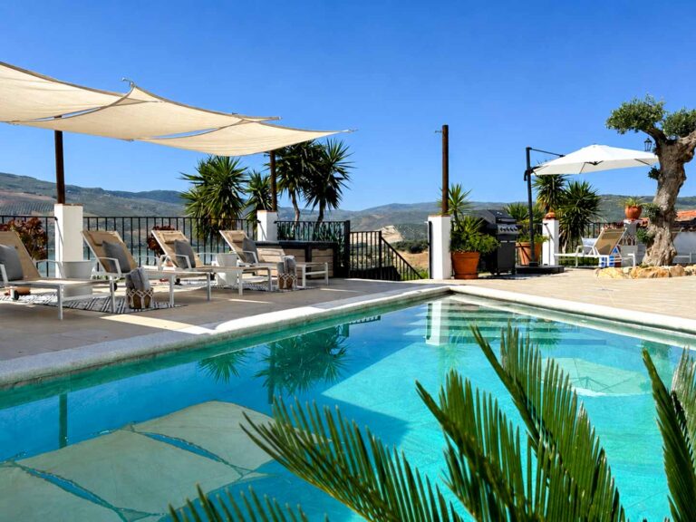 Blick über den Pool zu den Sonnenliegen